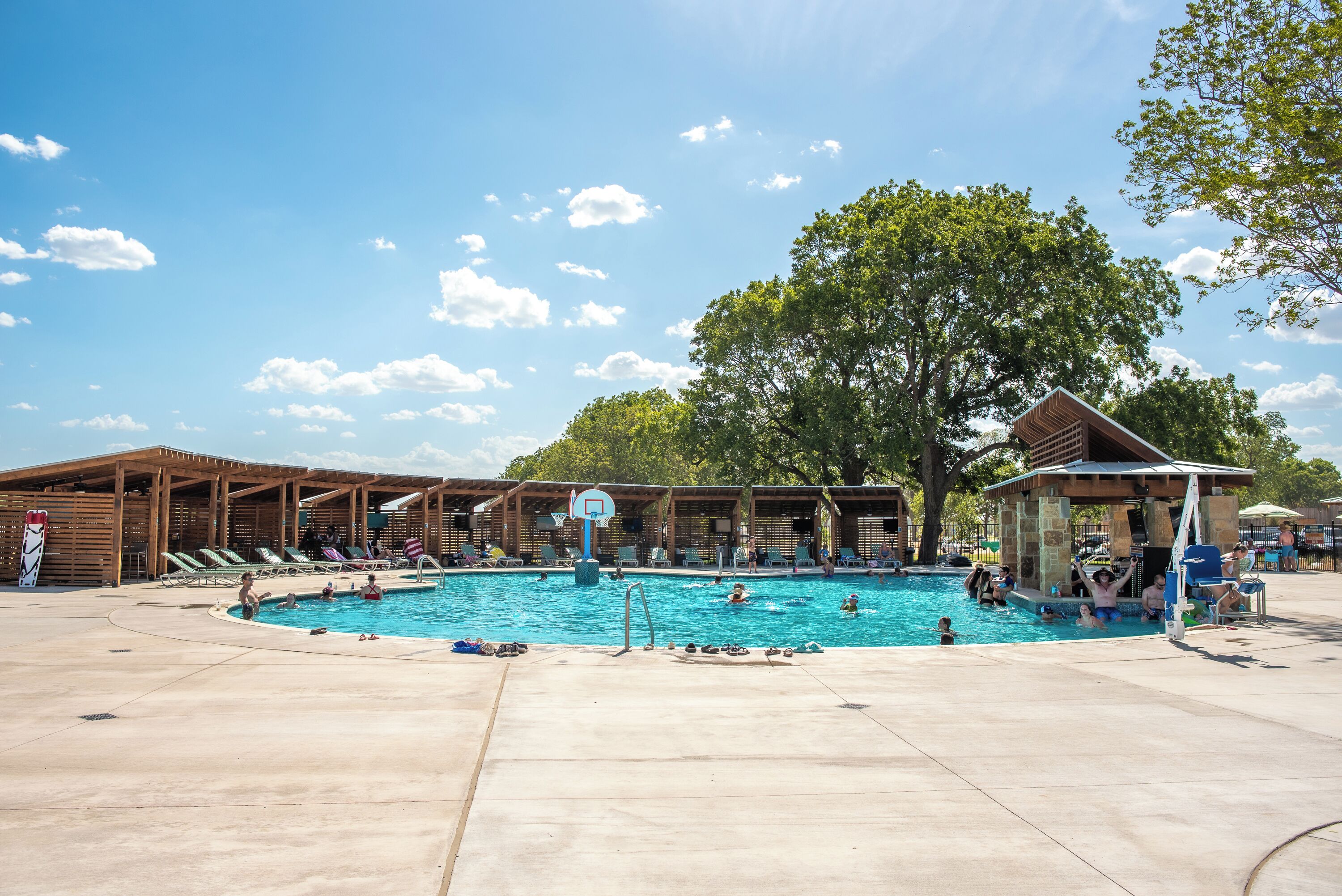 A swimming pool area with lounge chairs and a basketball hoop.