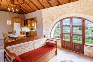 A cozy room with a wooden bench, stone wall, and a large arched window. - Villa Ostria Near Georgioupolis - 5BD 4BA 10pl (Apokoronas)
