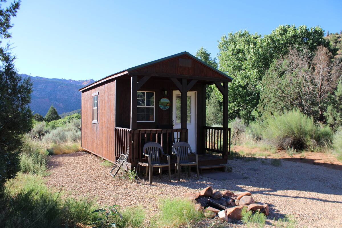 A wooden cabin with a porch and two chairs.