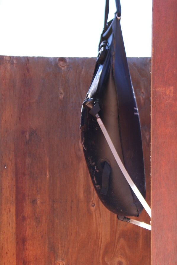 Un sac noir est accroché à une clôture en bois.