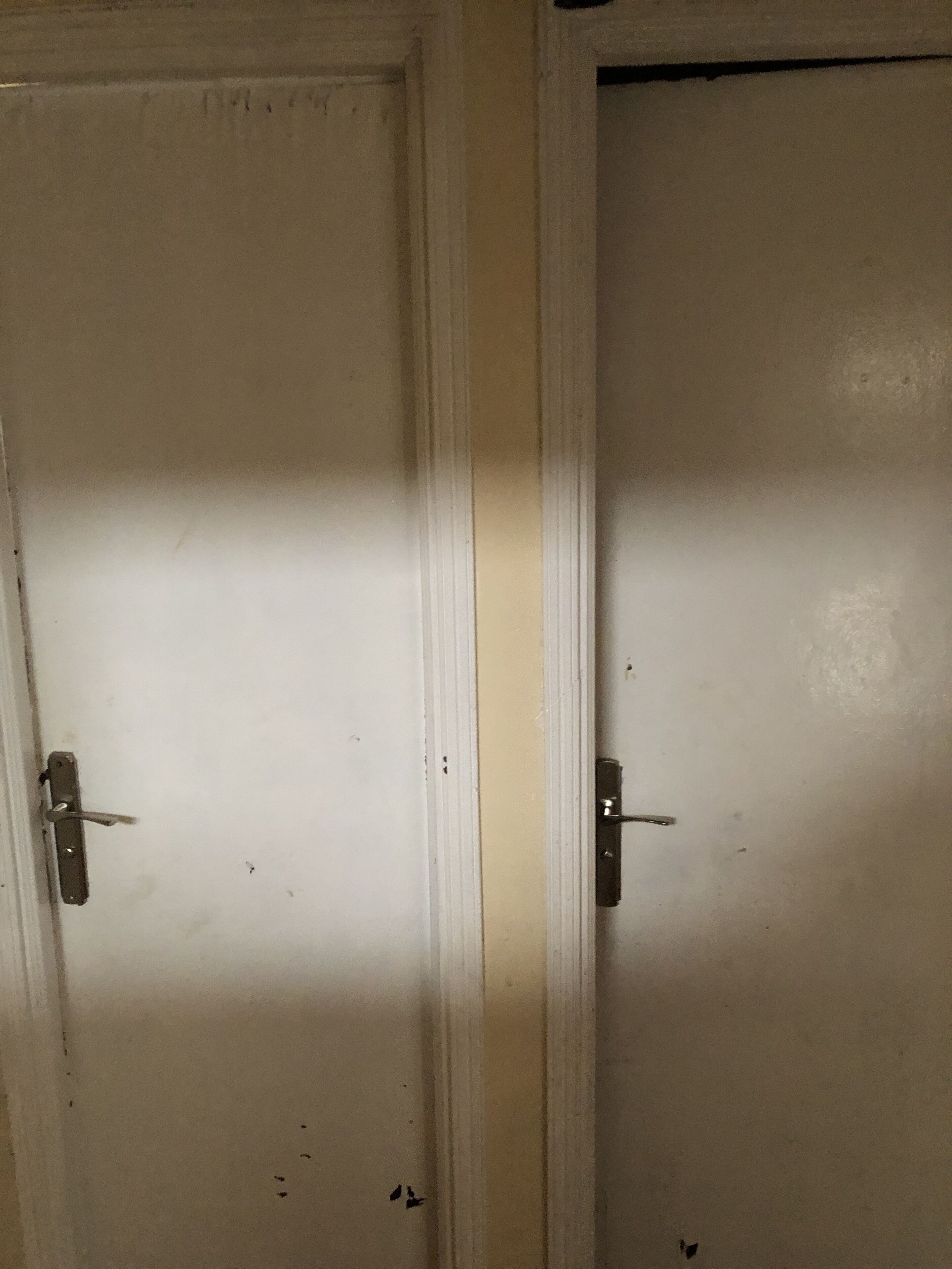 Two white doors with metal handles, one slightly ajar.