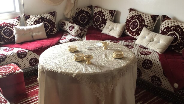 Een gezellige woonkamer met een ronde salontafel, gestreepte kussens en een rode bank.