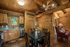 A wooden cabin interior with a dining area, kitchen, and a cozy seating area.