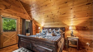 Un dormitorio de cabaña de madera con cama, banca, mesita de noche y ventana.