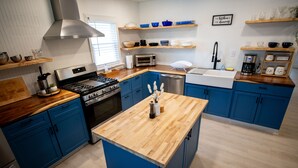 A modern kitchen with blue cabinets, a wooden island, stainless steel appliances, and wooden shelves. - Stylish Beach House, Hot Tub, Pet-Friendly🐾 (Norfolk)