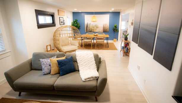 A living room with a sofa, a dining table, and chairs. There is a window, a plant, and a wall-mounted artwork. - Stylish Beach House, Hot Tub, Pet-Friendly🐾 (Norfolk)