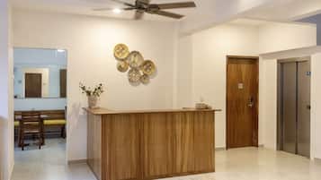 Zona de recepción con mostrador de madera, ventilador de techo y un plato decorativo en la pared.