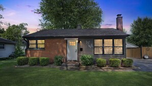 A single-story house with a brick facade, a white front door, and a chimney. - Modern Luxury Amenities Near Woodfield Mall 2 Bedroom Home by RedAwning (Rolling Meadows)