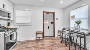 A modern kitchen with white cabinets, a stainless steel stove, and a bar area with stools. - Modern Luxury Amenities Near Woodfield Mall 2 Bedroom Home by RedAwning (Rolling Meadows)