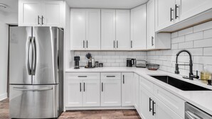 A modern kitchen with white cabinets, a stainless steel refrigerator, a sink, and a coffee maker. - Modern Luxury Amenities Near Woodfield Mall 2 Bedroom Home by RedAwning (Rolling Meadows)