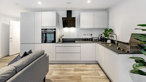 A modern kitchen with white cabinets, a built-in oven, and a black countertop. - Lacon House 2-bedroom apartment (Cambridge)