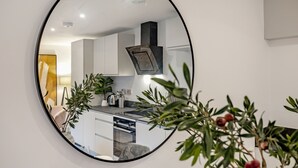 A modern kitchen with white cabinets, a black range hood, and a countertop with various appliances. - Lacon House 1-bedroom apartment (Cambridge)