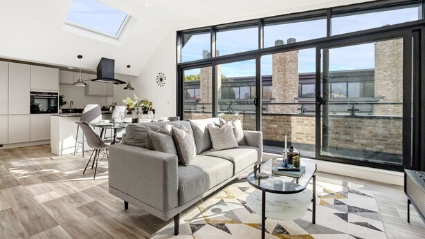 A modern living room with a sofa, coffee table, and a view of the city through large windows. - Lacon House 2-Bedroom Penthouse (Cambridge)