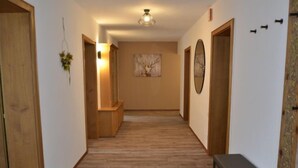 A hallway with wooden flooring, a bench, and a wall-mounted mirror. - Apart Hof Achenrainer by Interhome (Landeck)