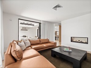 A modern living room with a sectional sofa, a coffee table, and a fireplace.