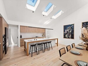 A modern kitchen with a central island, bar stools, and a dining area with a table set for four.