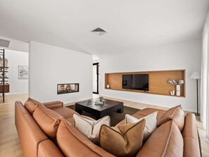 A modern living room with a leather sofa, a black coffee table, and a mounted TV.