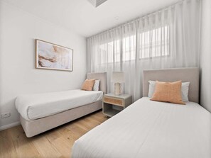 A bedroom with two beds, a bedside table, a lamp, and a painting on the wall. - Amila — Designer Coastal Retreat in Dunsborough (Dunsborough)