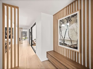 A modern hallway with wooden flooring, a bench, and a framed picture on the wall. - Amila — Designer Coastal Retreat in Dunsborough (Dunsborough)