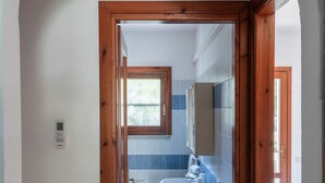 A bathroom with a white sink, blue tiles, a wooden door frame, and a window. - Simple Gem of Le Dimore di Budoni 1 Bedroom Apartment Sleeps 2 Persons (Budoni)