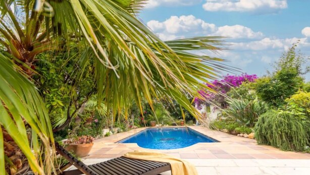 A pool surrounded by lush greenery and a lounge chair with a yellow towel. - Paraiso by Interhome (Deltebre)
