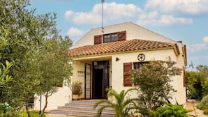 A two-story building with a tiled roof, a front door, and a small garden with steps leading to the entrance. - Paraiso by Interhome (Deltebre)