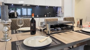 A modern kitchen with a dining area, equipped with a built-in oven, wine bottle, and glasses.