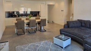 A modern apartment with a dining area, kitchen, and living room.