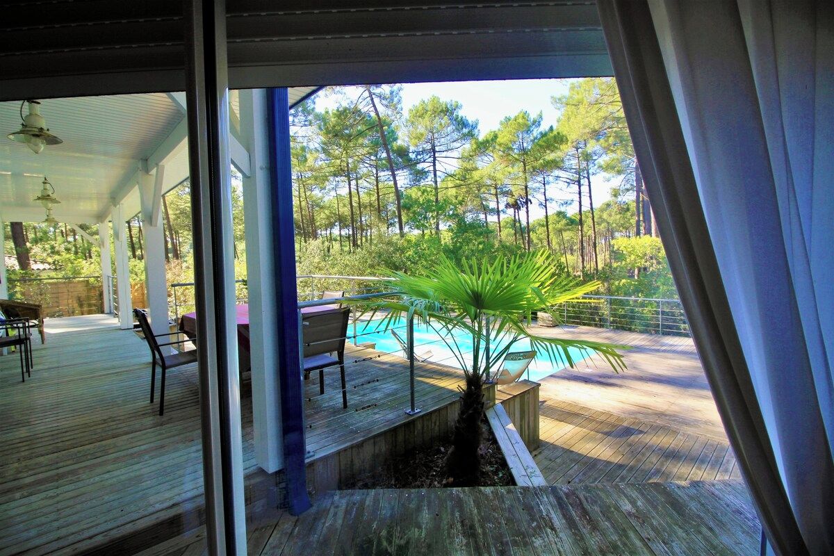 Terraza de madera con mobiliario exterior y vista a una piscina.