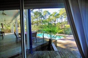 A wooden deck with outdoor seating and a view of a swimming pool. - House with pool and terrace facing the Golf G0275 (Lacanau-Ocean)