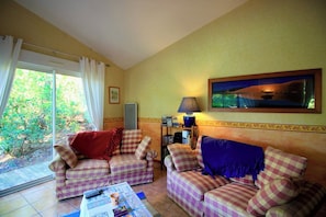 A living room with two checkered sofas, a coffee table with magazines, a lamp, and a painting on the wall.