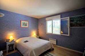 Un dormitorio con cama, mesitas de noche, una ventana y decoración en la pared.