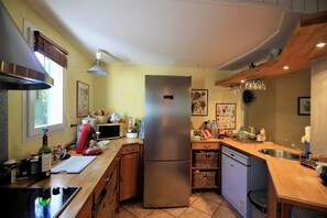 A kitchen with a stainless steel refrigerator, wooden cabinets, a microwave, and a sink.