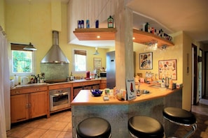 A kitchen with a central island, bar stools, a stainless steel range hood, and various kitchen appliances. - House with pool and terrace facing the Golf G0275 (Lacanau-Ocean)