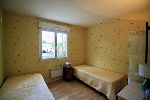 A room with two single beds, a window, a radiator, and a small table with a lamp. - House with pool and terrace facing the Golf G0275 (Lacanau-Ocean)