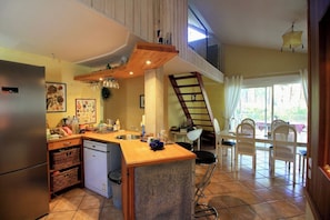 A kitchen with a wooden countertop, a dishwasher, and a dining area with a table and chairs. - House with pool and terrace facing the Golf G0275 (Lacanau-Ocean)