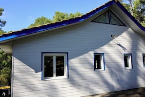 A white house with a blue roof, a chimney, and a window with a blue frame.