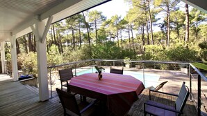 Une terrasse extérieure avec une piscine, entourée d’arbres.