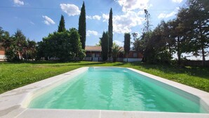 A rectangular swimming pool with a clear blue water surface, surrounded by a grassy area and trees. - Hostal San Martin de Montalbán (San Martin de Montalban)