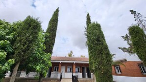 A building with a tiled roof, surrounded by tall, narrow trees. - Hostal San Martin de Montalbán (San Martin de Montalban)