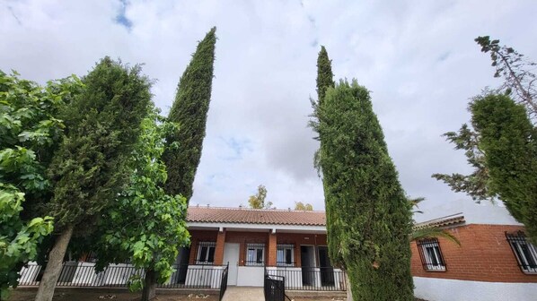 Un bâtiment doté d’un toit en tuiles, entouré d’arbres hauts et étroits.