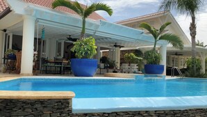 A pool area with a covered patio, stone walls, and large potted plants. - "srvittinivillas Lc01  Resorts / Spacious/ Family/ Group/ Best Loc" (La Romana)