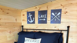 Une chambre à coucher avec une tête de lit en bois, un lit recouvert d’une literie bleu marine et trois éléments de décoration murale sur le thème de la marine.