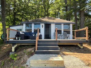 Een chalet met terras, buitenmeubels en een trap naar de ingang.