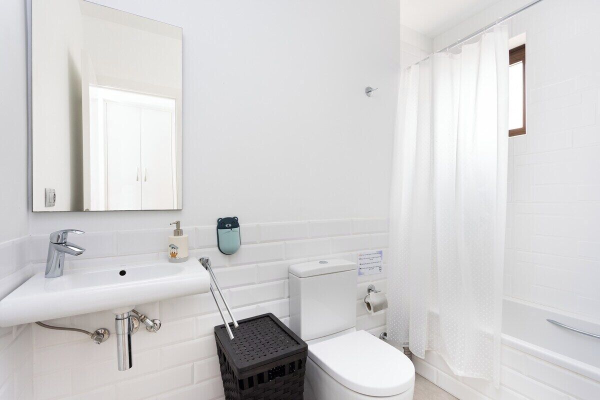 A bathroom with a white sink, a mirror, a toilet, and a shower curtain.