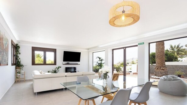 Un salon moderne avec une table à manger en verre, un canapé blanc et un téléviseur.