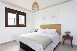 A bedroom with a bed, a bedside table, a hanging light fixture, and artwork on the wall.