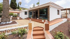 Une maison moderne dotée d’un patio, d’une fontaine en pierre et d’une variété de plantes.