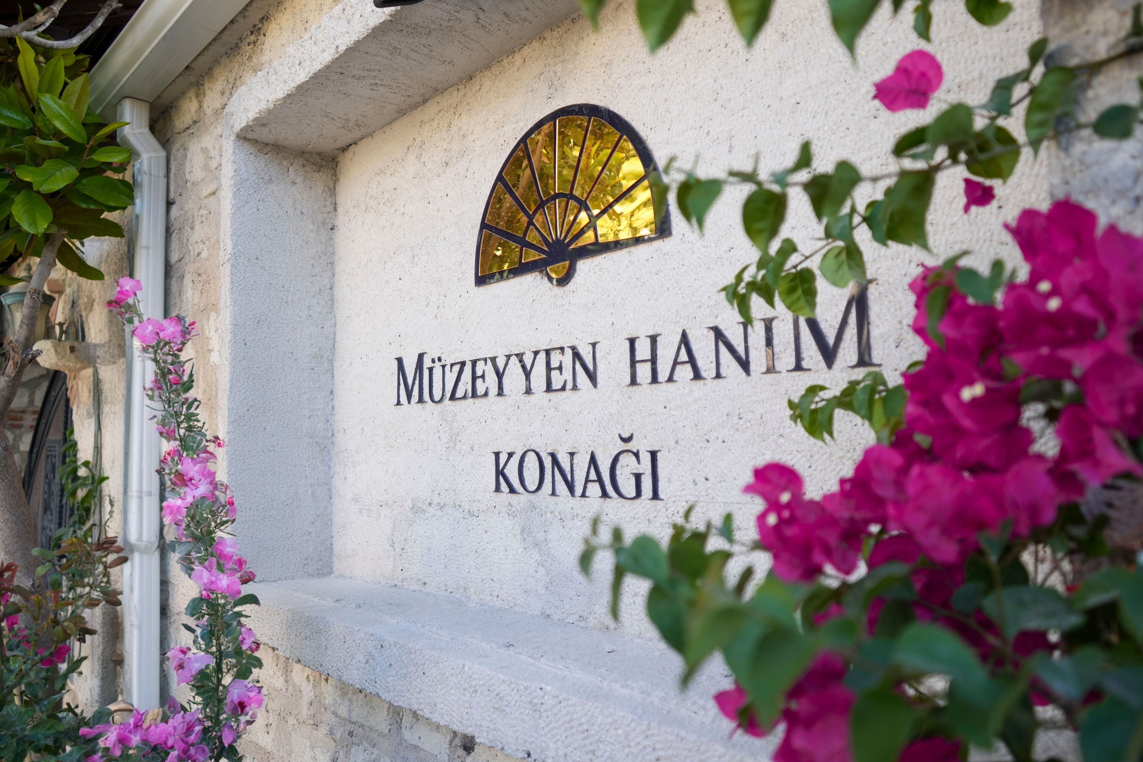 Fachada de un edificio con el nombre "MUZEYYEN HANIM KONAGI" y un motivo decorativo de sol.