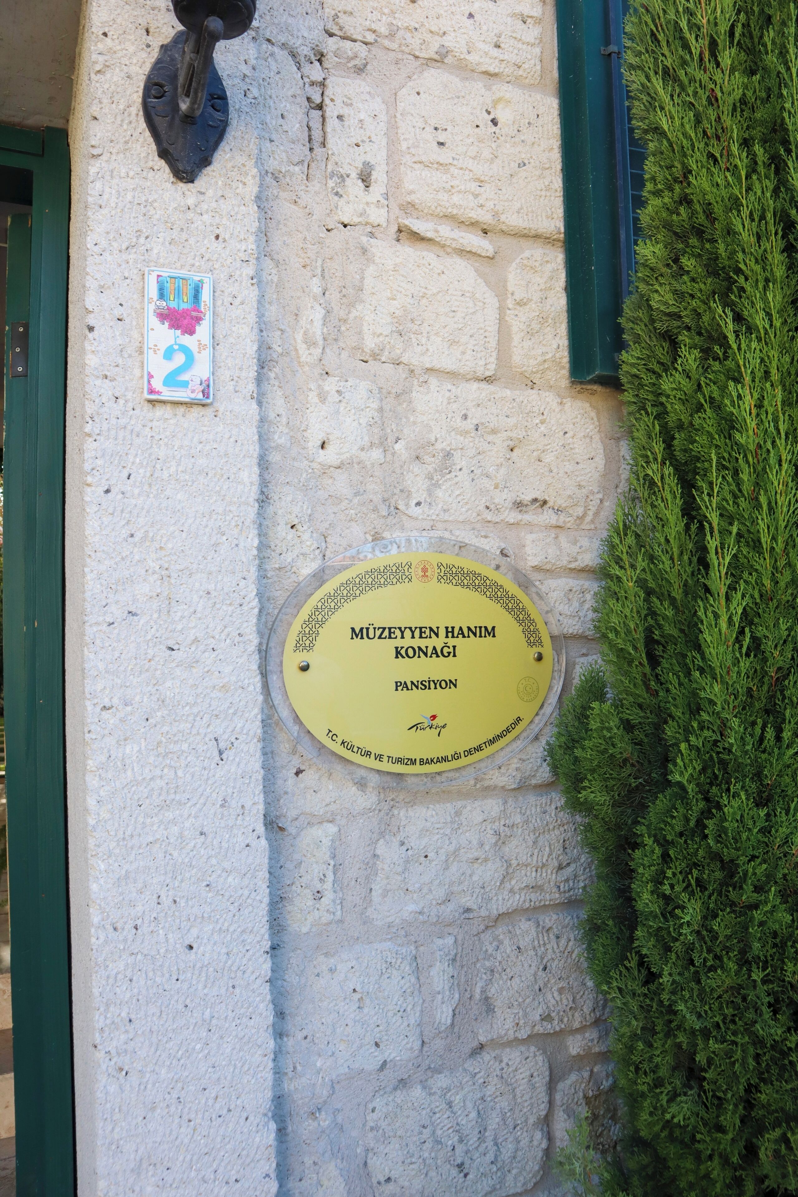 A plaque on a stone wall with a number sign and a green door frame.